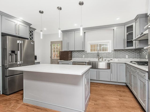 kitchen featuring pendant lighting, a kitchen island, backsplash, appliances with stainless steel finishes, and sink