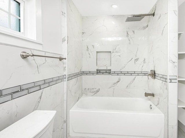 bathroom with toilet and tiled shower / bath combo