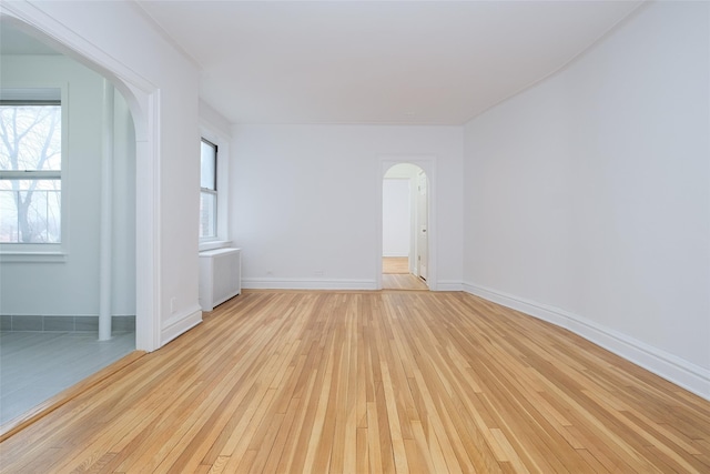 unfurnished room with radiator and light wood-type flooring