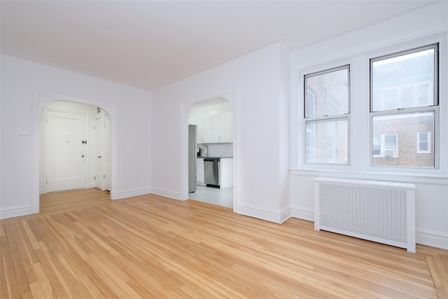 unfurnished room with radiator heating unit and light hardwood / wood-style flooring