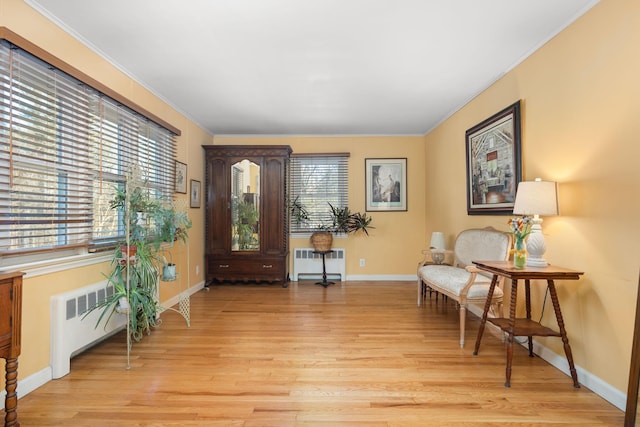 living area featuring light hardwood / wood-style floors, radiator heating unit, and crown molding