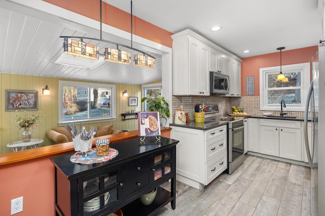 kitchen with decorative light fixtures, sink, white cabinetry, and appliances with stainless steel finishes