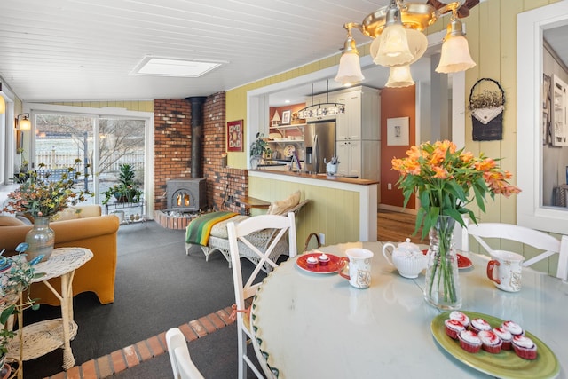 dining room with vaulted ceiling and a wood stove