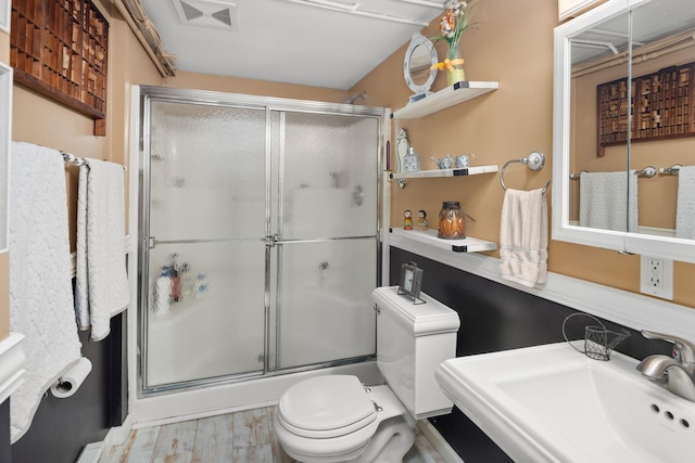 bathroom featuring toilet, a shower with door, sink, and hardwood / wood-style floors