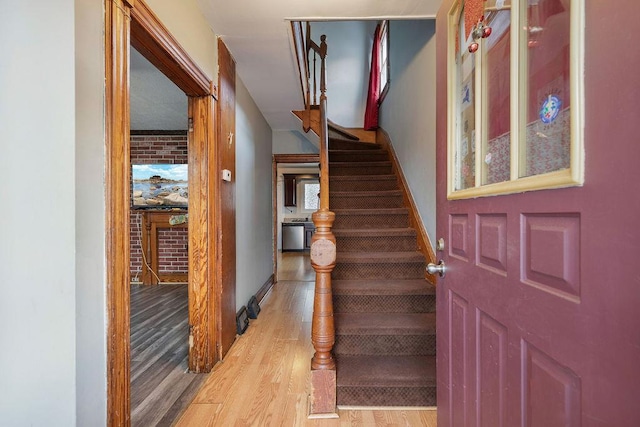 entryway with brick wall and light hardwood / wood-style floors