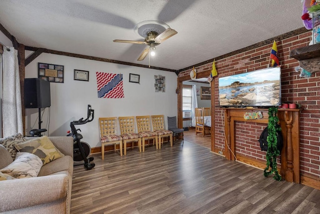 living room with a textured ceiling, ceiling fan, hardwood / wood-style floors, and brick wall