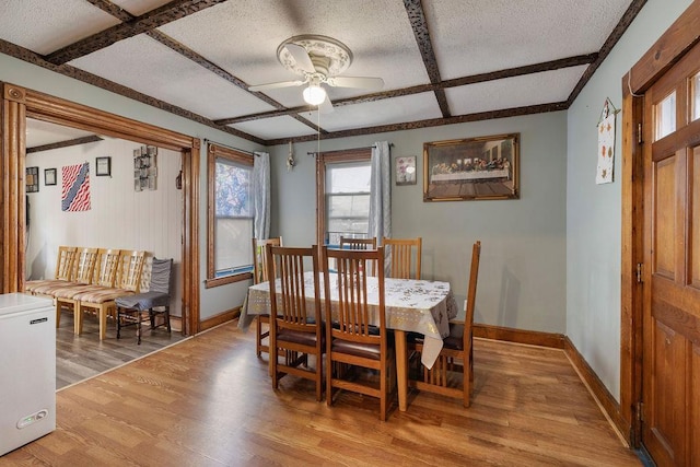 dining room with coffered ceiling, beamed ceiling, ceiling fan, a textured ceiling, and light hardwood / wood-style flooring