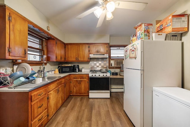 kitchen featuring range, white fridge, a baseboard heating unit, light wood-type flooring, and fridge