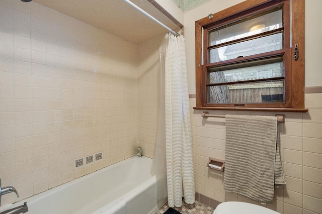 bathroom featuring tile walls, shower / bath combo with shower curtain, and toilet