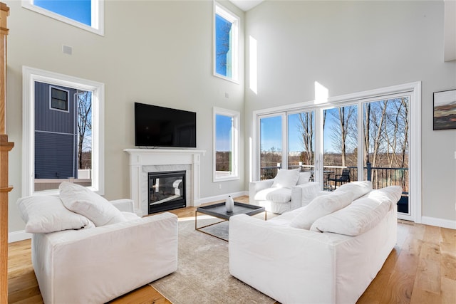 living room with a towering ceiling, a fireplace, and plenty of natural light