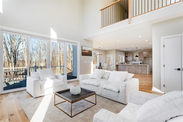 living room featuring light hardwood / wood-style flooring, an inviting chandelier, and a towering ceiling