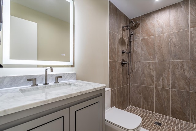 bathroom with a tile shower, vanity, and toilet