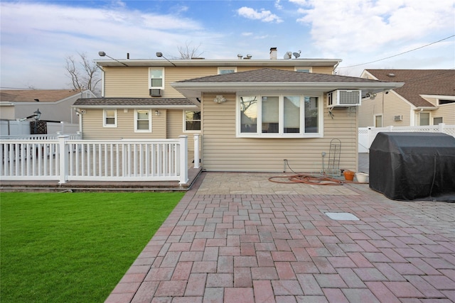 rear view of house with a patio area, a yard, and a wall unit AC