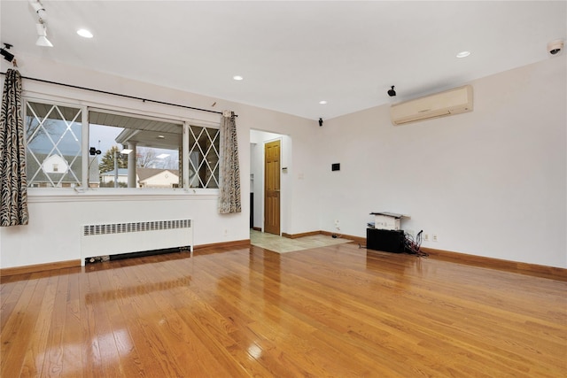 empty room with hardwood / wood-style flooring, radiator, and a wall unit AC