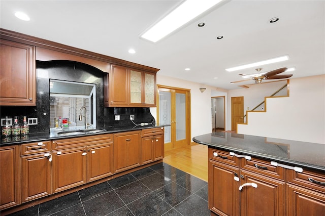 kitchen with ceiling fan, sink, backsplash, and dark stone countertops