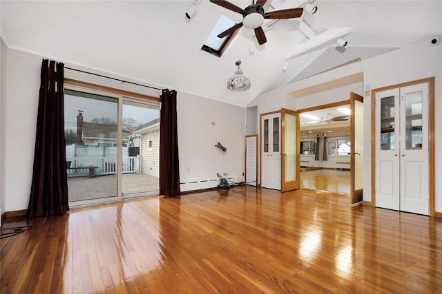 empty room featuring ceiling fan, vaulted ceiling with skylight, hardwood / wood-style floors, and a baseboard radiator