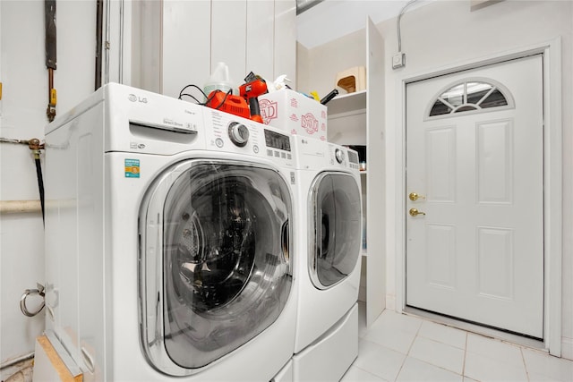 clothes washing area with light tile patterned floors and washer and clothes dryer