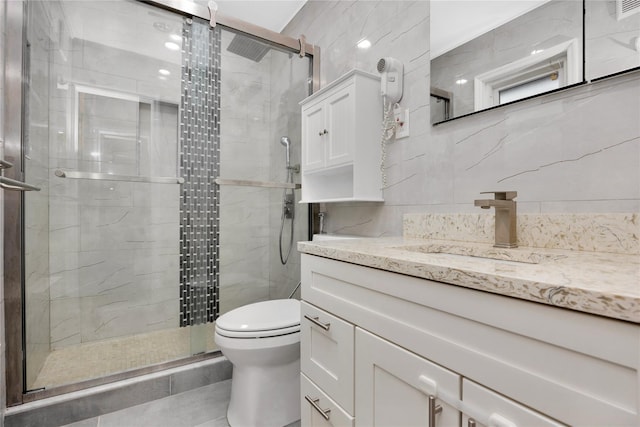 bathroom with an enclosed shower, vanity, tile walls, and toilet