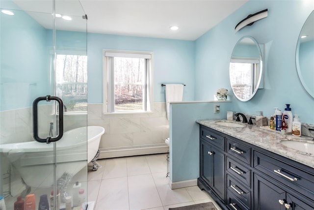 bathroom featuring a bathing tub, toilet, tile patterned floors, a baseboard heating unit, and vanity