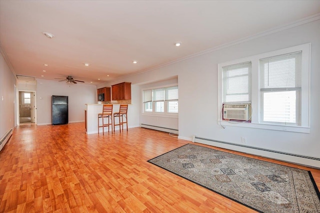 unfurnished living room with light wood-type flooring, baseboard heating, plenty of natural light, and ornamental molding