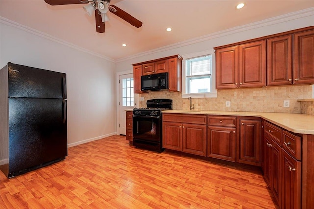 kitchen featuring light hardwood / wood-style floors, ceiling fan, tasteful backsplash, crown molding, and black appliances