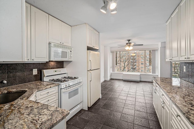 kitchen with dark stone counters, white appliances, and white cabinets