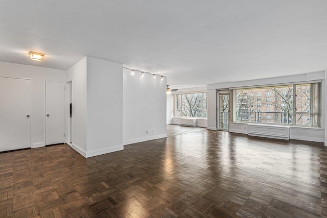 interior space with an AC wall unit, ceiling fan, and dark parquet floors