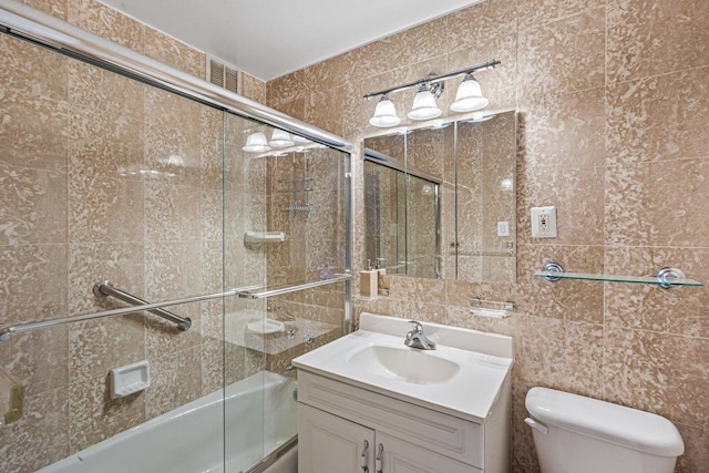 full bathroom featuring toilet, vanity, and shower / bath combination with glass door