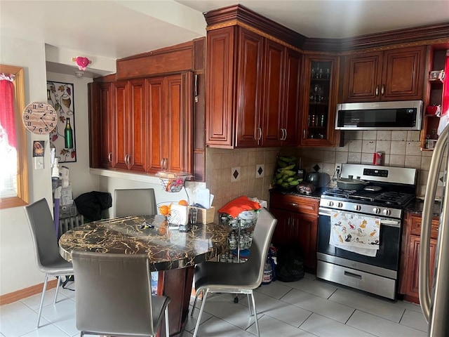 kitchen with backsplash, light tile patterned floors, a kitchen bar, and appliances with stainless steel finishes