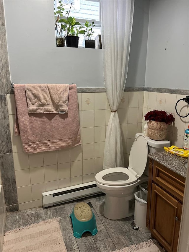 bathroom featuring tile walls, vanity, a baseboard radiator, and toilet