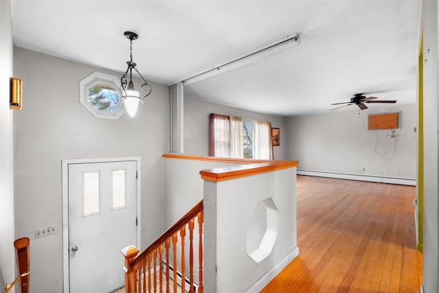 foyer entrance with baseboard heating, wood-type flooring, and ceiling fan