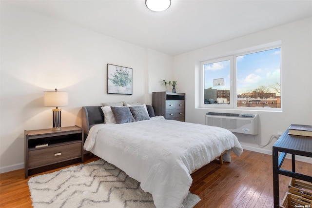 bedroom with a wall mounted air conditioner and wood-type flooring