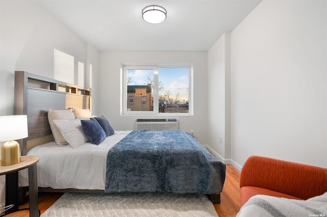 bedroom featuring hardwood / wood-style flooring and an AC wall unit