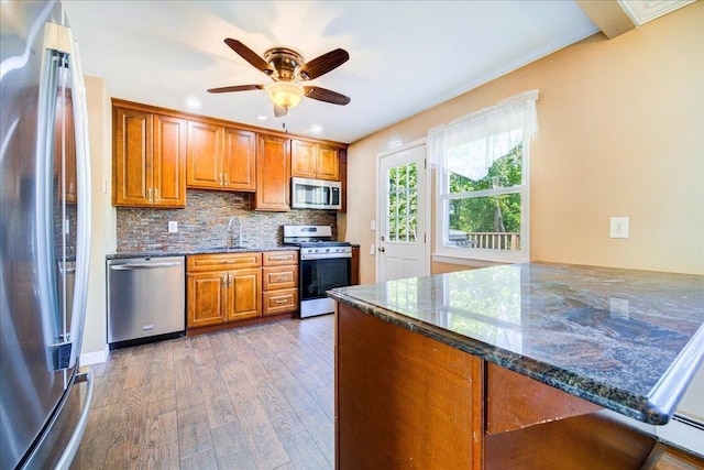 400 Philo St, New Windsor, NY 12553 - kitchen featuring stainless steel appliances, brown cabinetry, wood finished floors, a sink, and dark stone counters