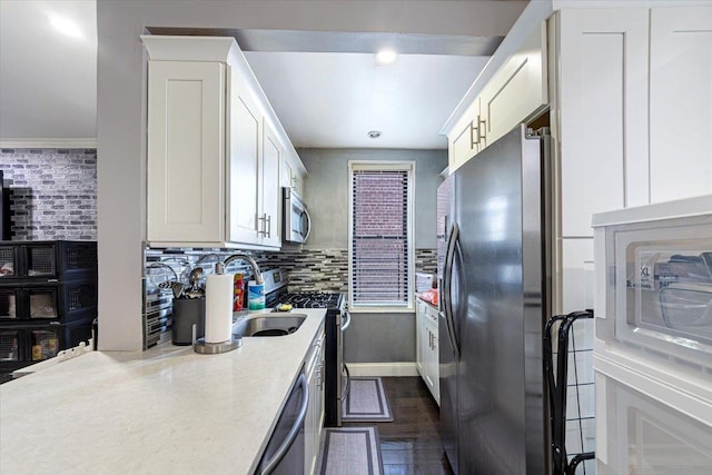 kitchen with sink, white cabinetry, decorative backsplash, crown molding, and appliances with stainless steel finishes