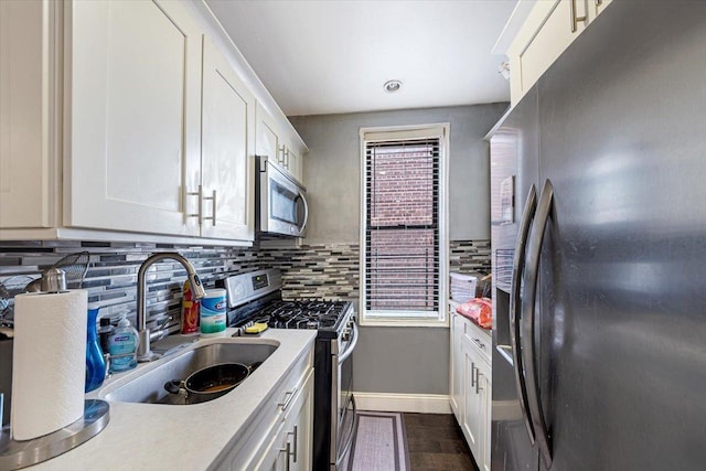 kitchen featuring white cabinets, appliances with stainless steel finishes, tasteful backsplash, and sink