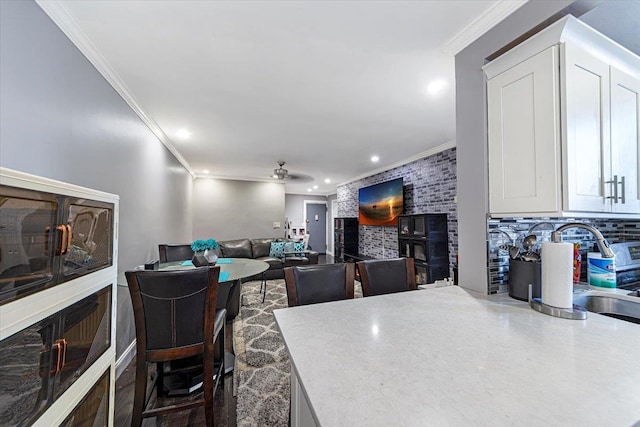 dining room featuring ceiling fan, crown molding, a wood stove, and sink