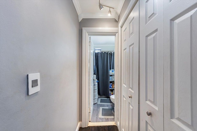 corridor with track lighting, ornamental molding, and dark wood-type flooring