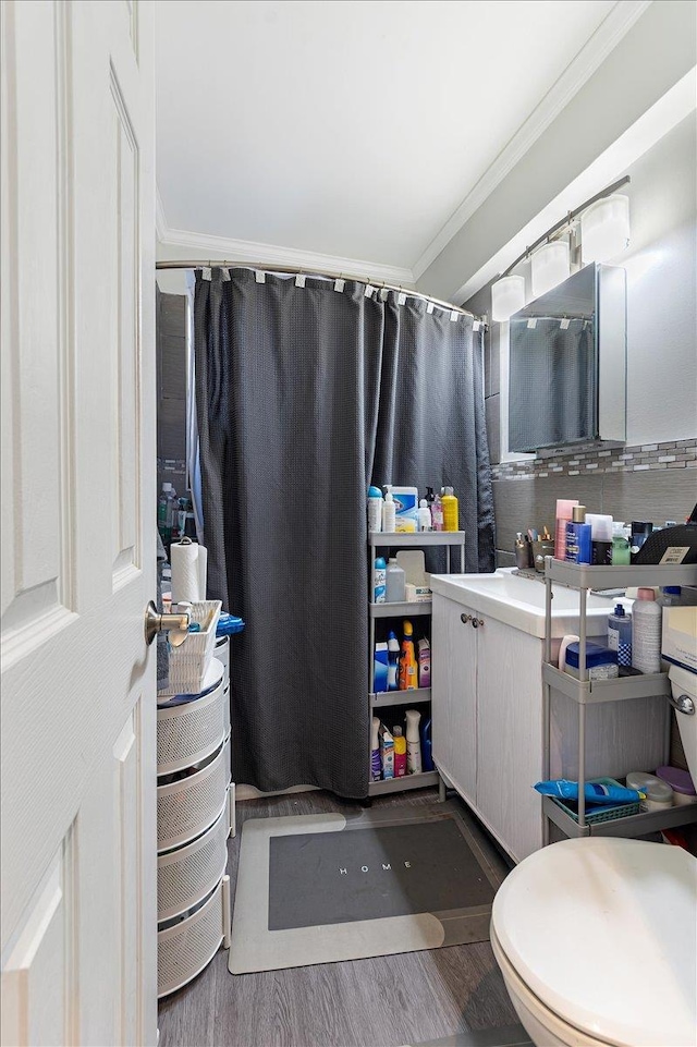 bathroom with hardwood / wood-style floors, toilet, vanity, ornamental molding, and backsplash