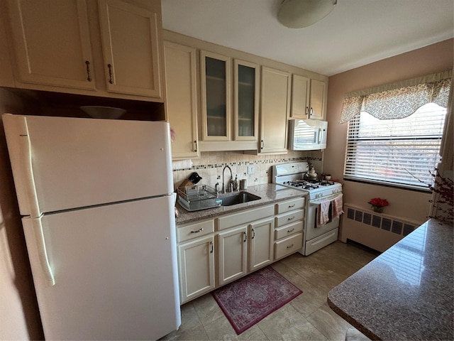 kitchen featuring sink, white appliances, dark stone countertops, tasteful backsplash, and radiator heating unit