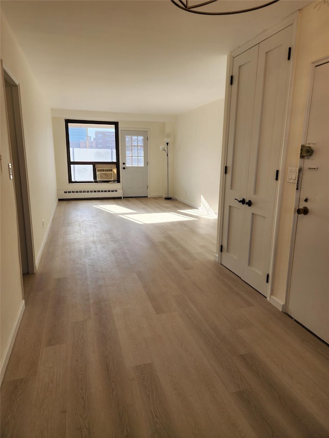 corridor featuring light wood-type flooring and a baseboard heating unit