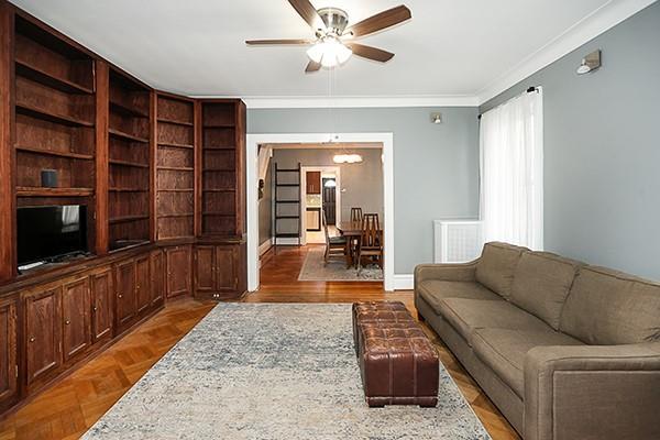 living room with parquet flooring, ceiling fan, and crown molding