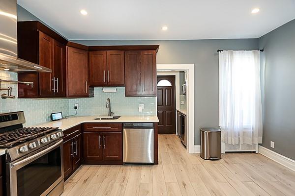 kitchen featuring sink, stainless steel appliances, a wealth of natural light, and wall chimney exhaust hood