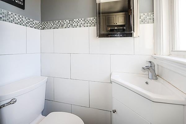 bathroom featuring tile walls and toilet