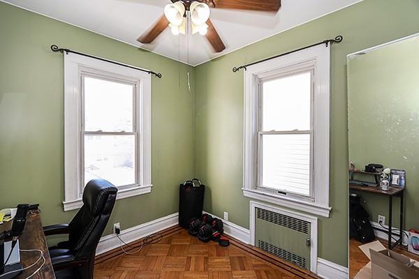 office with radiator, parquet flooring, ceiling fan, and a healthy amount of sunlight