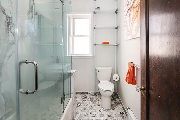 bathroom featuring a shower with door, tile patterned floors, and toilet