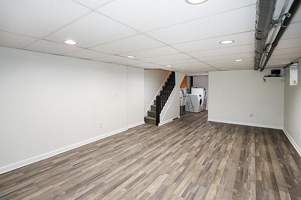 basement featuring washing machine and clothes dryer, a paneled ceiling, and hardwood / wood-style floors