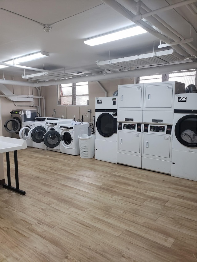 laundry area with stacked washing maching and dryer, washing machine and dryer, and light wood-type flooring