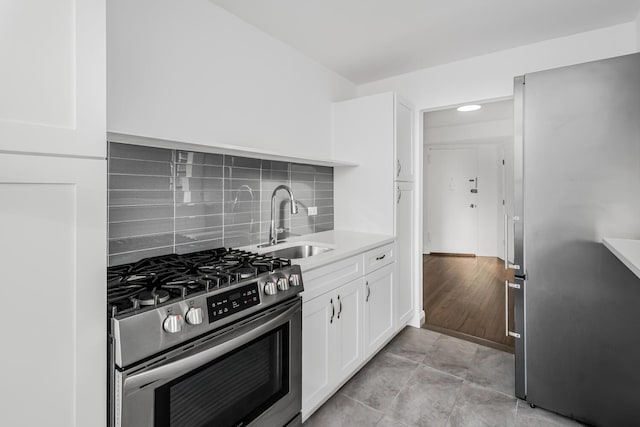 kitchen with sink, white cabinets, tasteful backsplash, and appliances with stainless steel finishes