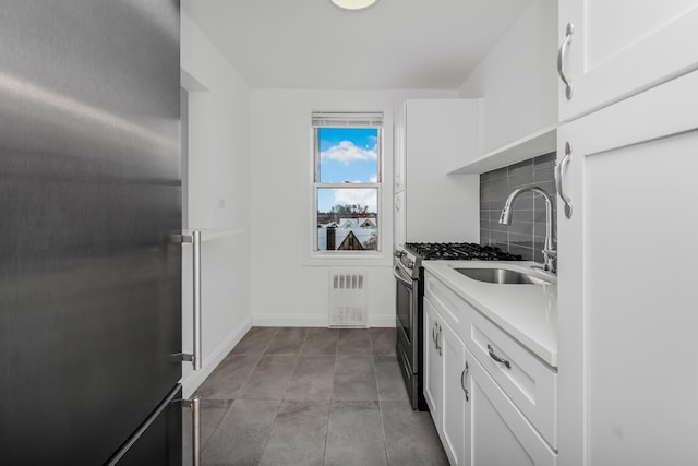 kitchen featuring appliances with stainless steel finishes, white cabinets, sink, and decorative backsplash